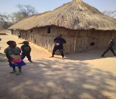 Thatched school buildings at Nanungwe Primary School with children playing in the open yard